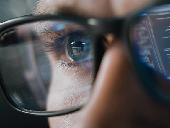 An engineer reading code reflected in their glasses