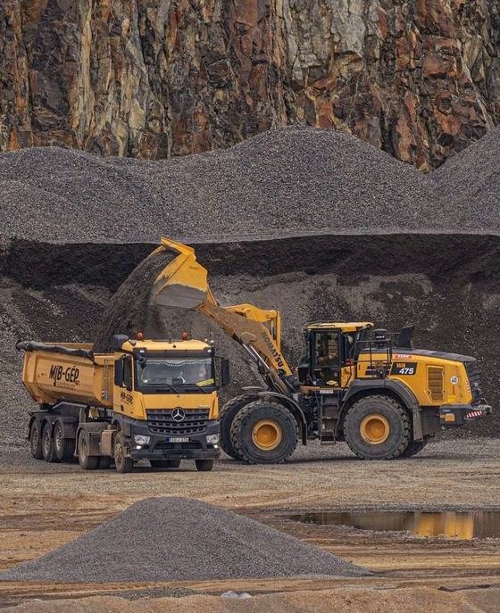A wheel loader filling a haulage truck at a quarry