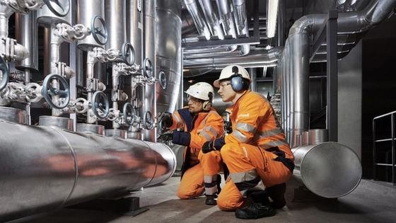 Two engineers checking valves in a plant of insulated pipework