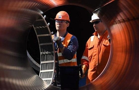 Two engineers inspecting a large steel pipe section