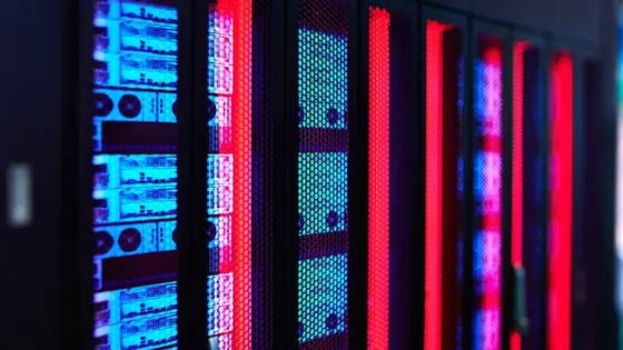 A row of server racks lit in blue and red inside a data hall