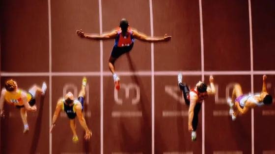 Overhead view of hurdlers mid-stride across the lanes of a track