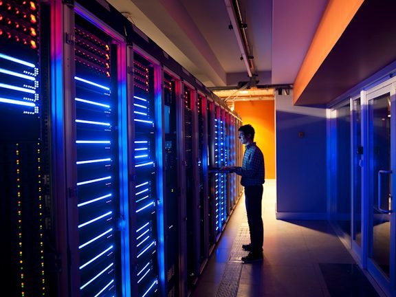 An engineer working along a lit row of data centre racks