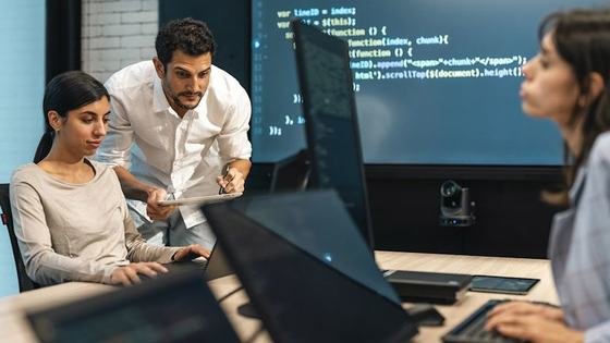 Developers reviewing code together in front of a wall of source