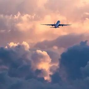 An aircraft climbing above a bank of cloud at sunset