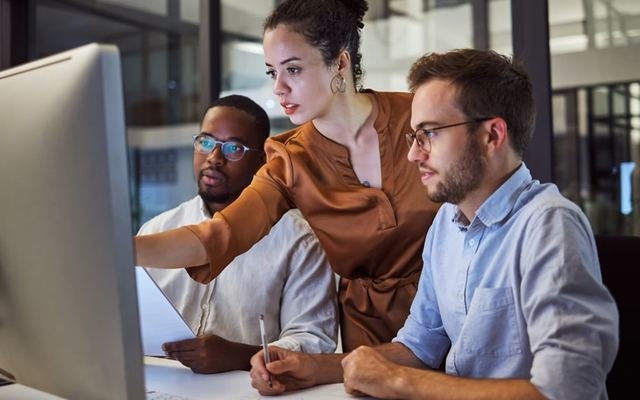 Three colleagues reviewing a report together on screen
