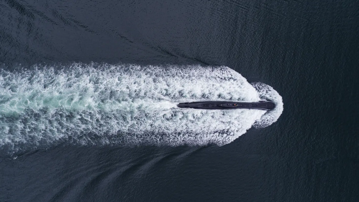 A submarine running on the surface, seen from directly above, its wake spreading behind it