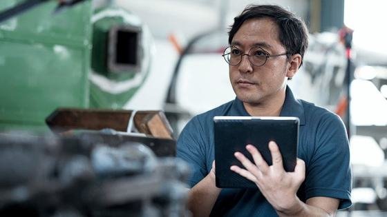 An engineer consulting a tablet on a factory floor