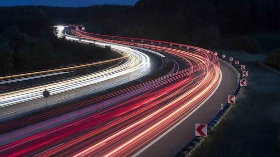 Long-exposure light trails along a curving road at dusk